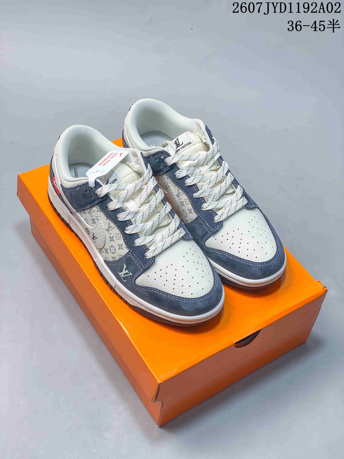 Pair of white and navy low-top monogram-style sneakers on an orange box