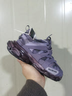 Angled view of the lavender Balenciaga Track sneaker held in hand, showing the lace area, mesh sections, toe branding, and segmented outsole.
