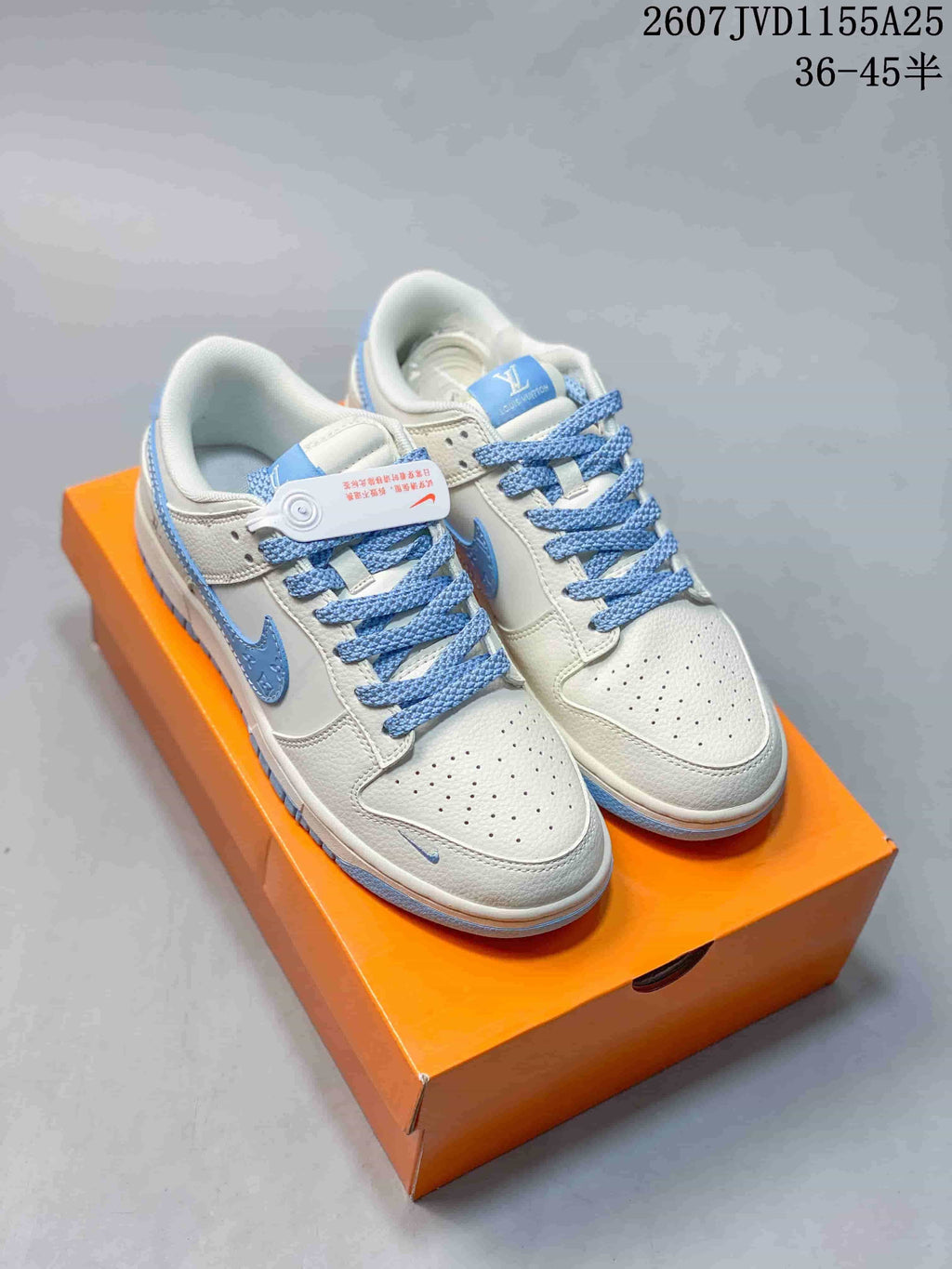 Pair of white and light blue Nike SB Dunk Low Pro sneakers displayed on an orange shoebox.