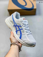 Angled side view of a white and blue ASICS Gel-Contend 4 sneaker showing the mesh upper, blue side detailing, and textured outsole.
