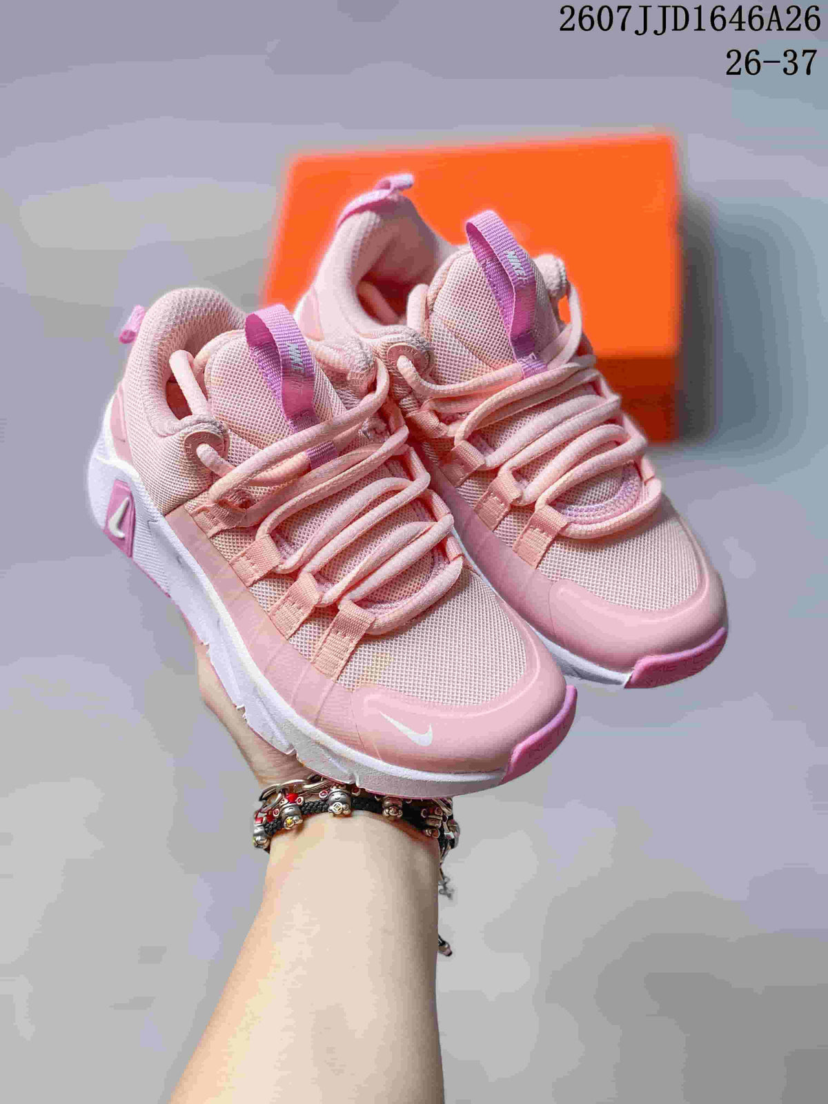 Pair of pink and white Nike children's training shoes shown from an angled top view with an orange shoebox behind them.