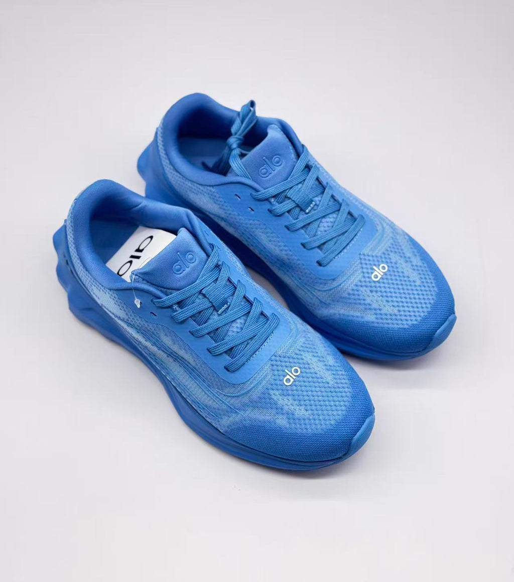 Top three-quarter view of the pair of blue Alo sneakers showing the tongues, laces and toe branding.