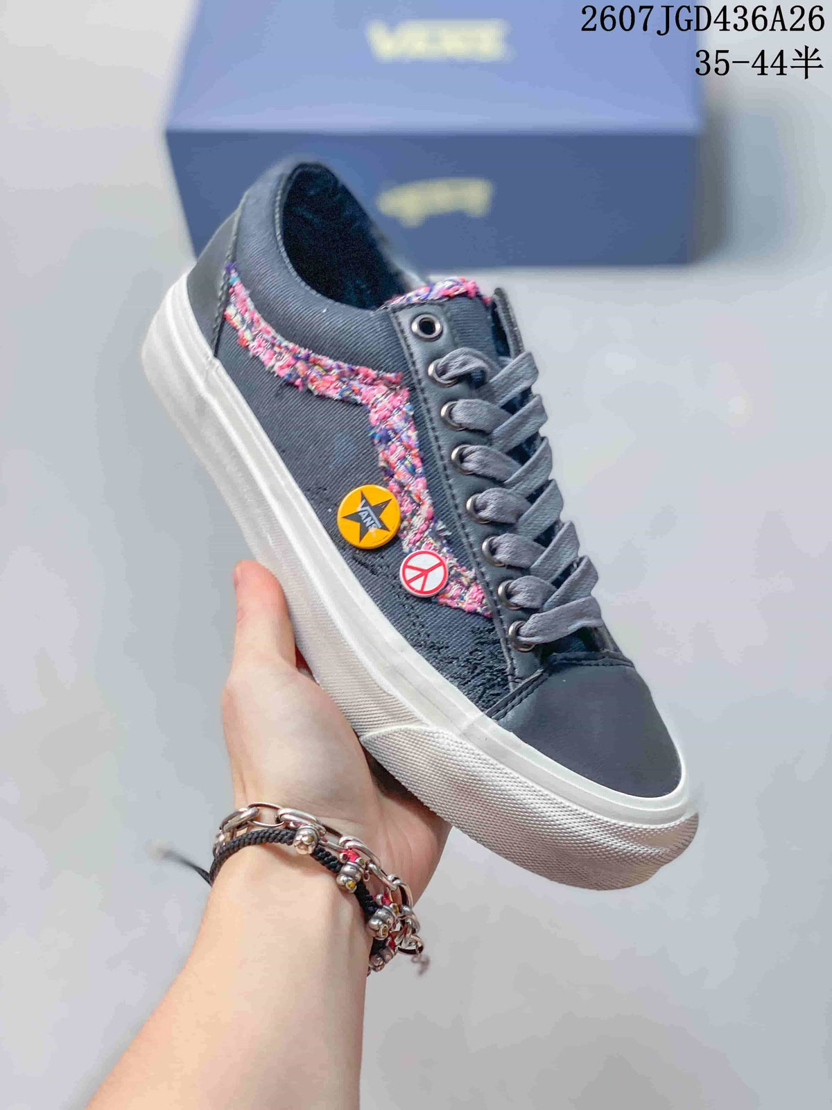 Angled side view showing the dark navy sneaker, multicolor side detailing, decorative pins, white stripe and white rubber sole.