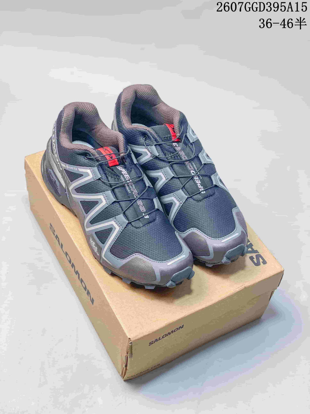 Pair of dark gray and navy Salomon Speedcross 3 shoes displayed on a Salomon box; image text shows style code 2607GGD395A15 and size range 36–46.
