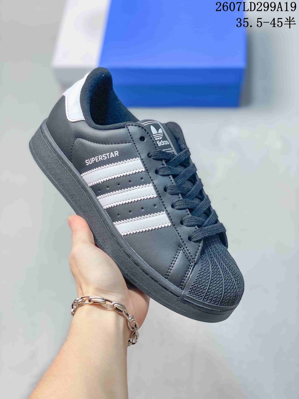 Black adidas Superstar sneaker with white serrated stripes and matching dark sole.