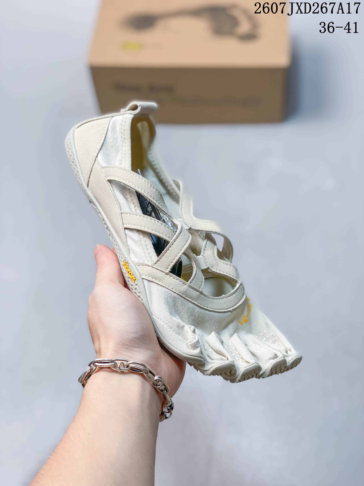 Close view of a white Vibram five-toe shoe held in hand, showing the side straps and textured toe sections.