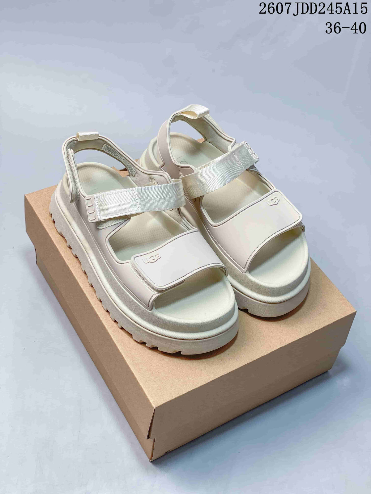 Pair of light white UGG GoldenGlow platform sandals displayed on a box, with two front straps and rear straps visible.