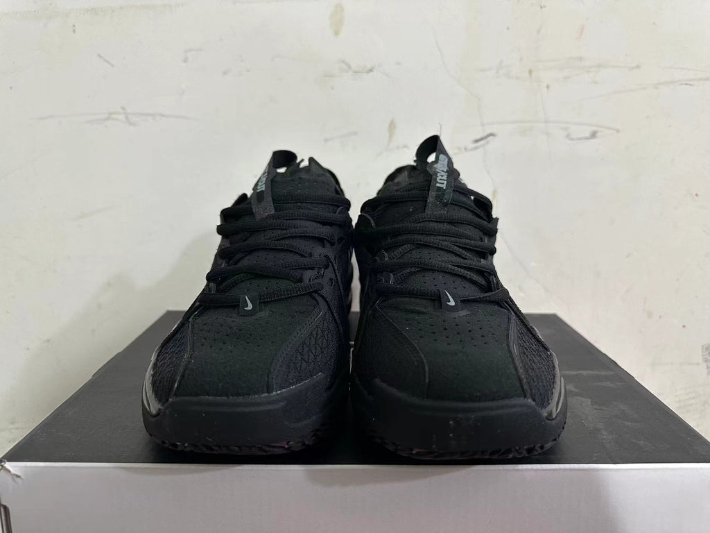 Front view of all-black Nike sneakers with lace-up closure and perforated upper
