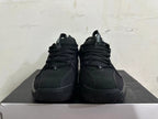 Front view of all-black Nike sneakers with lace-up closure and perforated upper