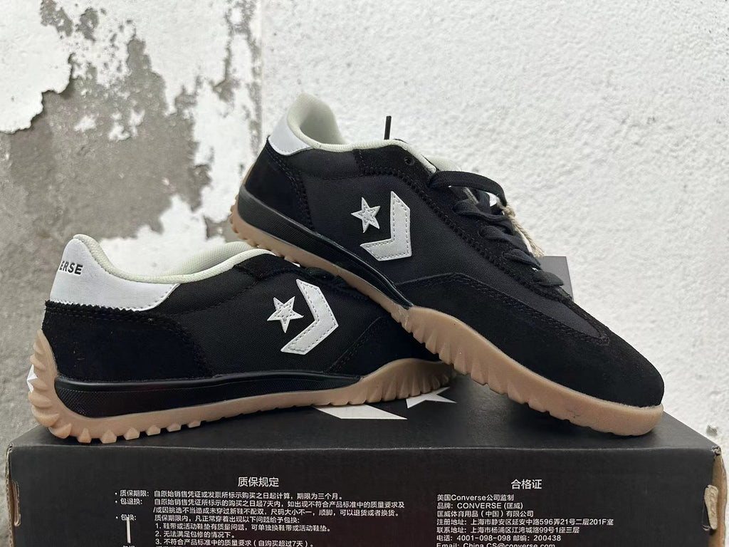 Pair of black Converse trainer-style sneakers with white accents and gum-colored outsoles.