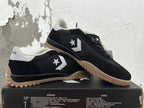 Pair of black Converse trainer-style sneakers with white accents and gum-colored outsoles.