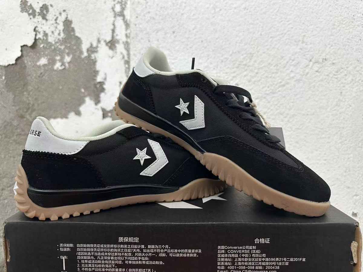 Pair of black Converse trainer-style sneakers with white accents and gum-colored outsoles.