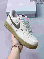 Cream low-top sneaker with dark gray side Swoosh, decorative metal details and pale olive-colored outsole.