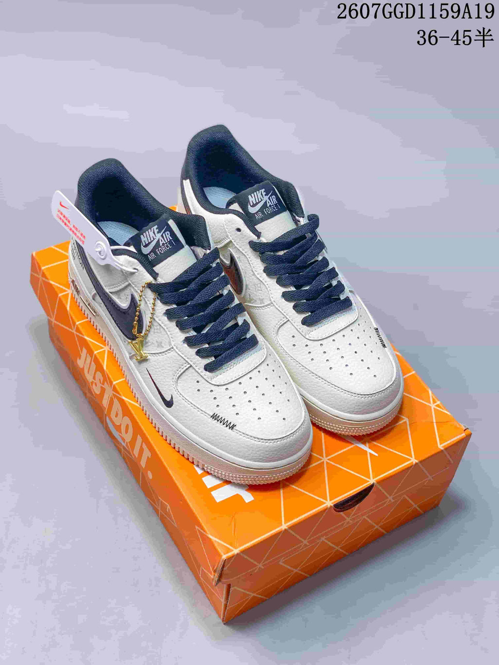 Pair of white and black Nike Air Force 1 low-top sneakers displayed on an orange shoe box; image text shows style code 2607GGD1159A19 and size range 36–45.