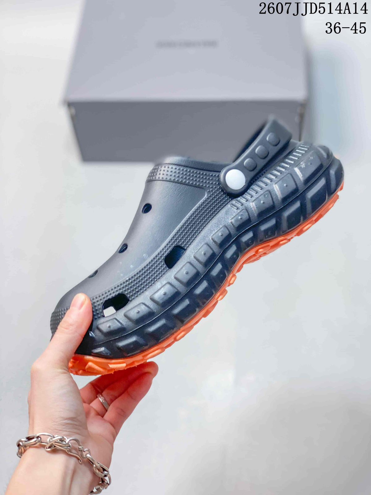 Side view of the black clog showing the perforated upper, adjustable strap, chunky outsole, and orange tread.