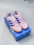 Pink Adidas Gazelle sneakers with blue side stripes and gum-colored soles displayed on an Adidas shoe box.