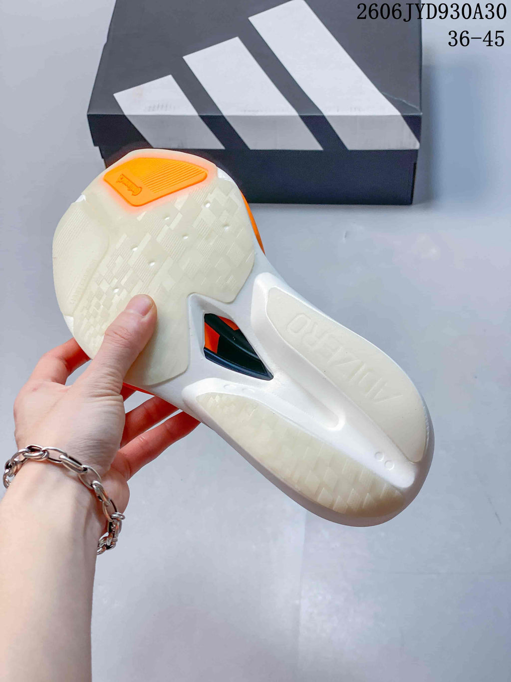 Underside of a running shoe showing the white sole and orange heel detail
