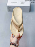 Top view of a beige New Balance thong sandal showing the textured footbed, toe post and embossed branding.