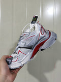 Close-up view of a white, silver, red, and black layered sneaker with mesh-textured panels and contrast overlays.