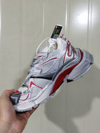 Close-up view of a white, silver, red, and black layered sneaker with mesh-textured panels and contrast overlays.
