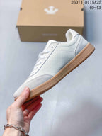 Side profile showing the white and light grey upper, low-top shape, laces, and gum-colored sole.