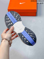 Close view of the patterned black, white and blue rubber outsole of the Nike running shoe beside an orange shoebox.