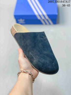 Close-up side view of a black adidas Adimule mule slide showing the closed toe, slip-on upper, and Trefoil branding.