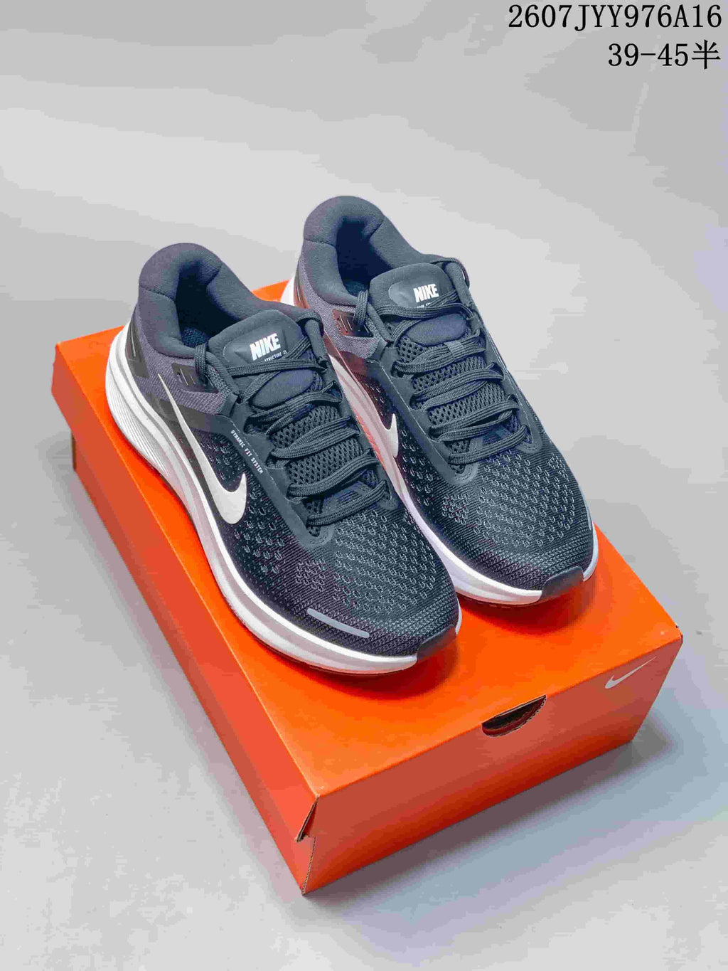 Pair of dark gray and white Nike Zoom Structure 23 sneakers displayed on an orange shoe box.