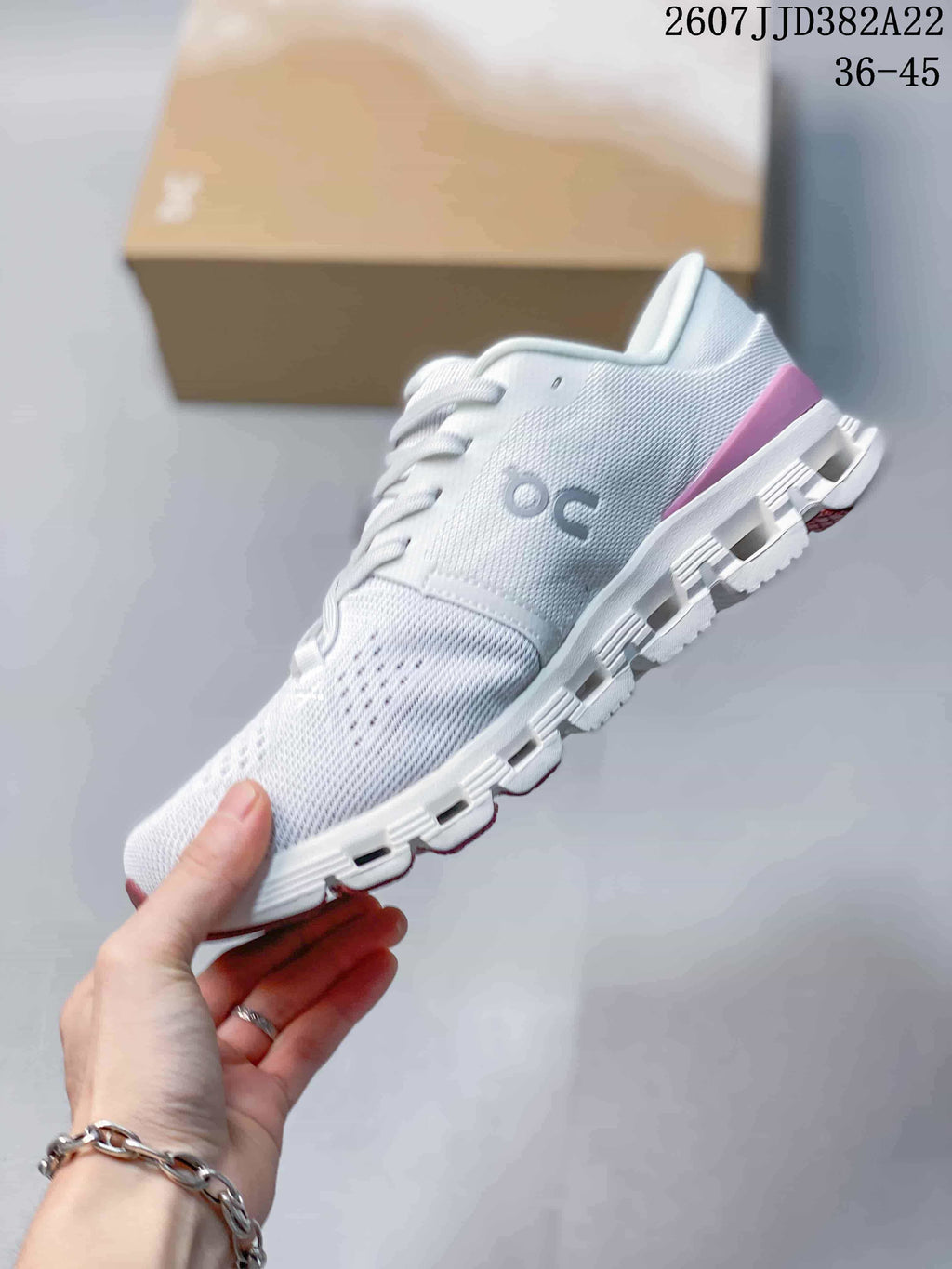 Side profile of the white and pink low-top sneaker showing the engineered knit-style upper, On logo, lace system, and segmented sole.