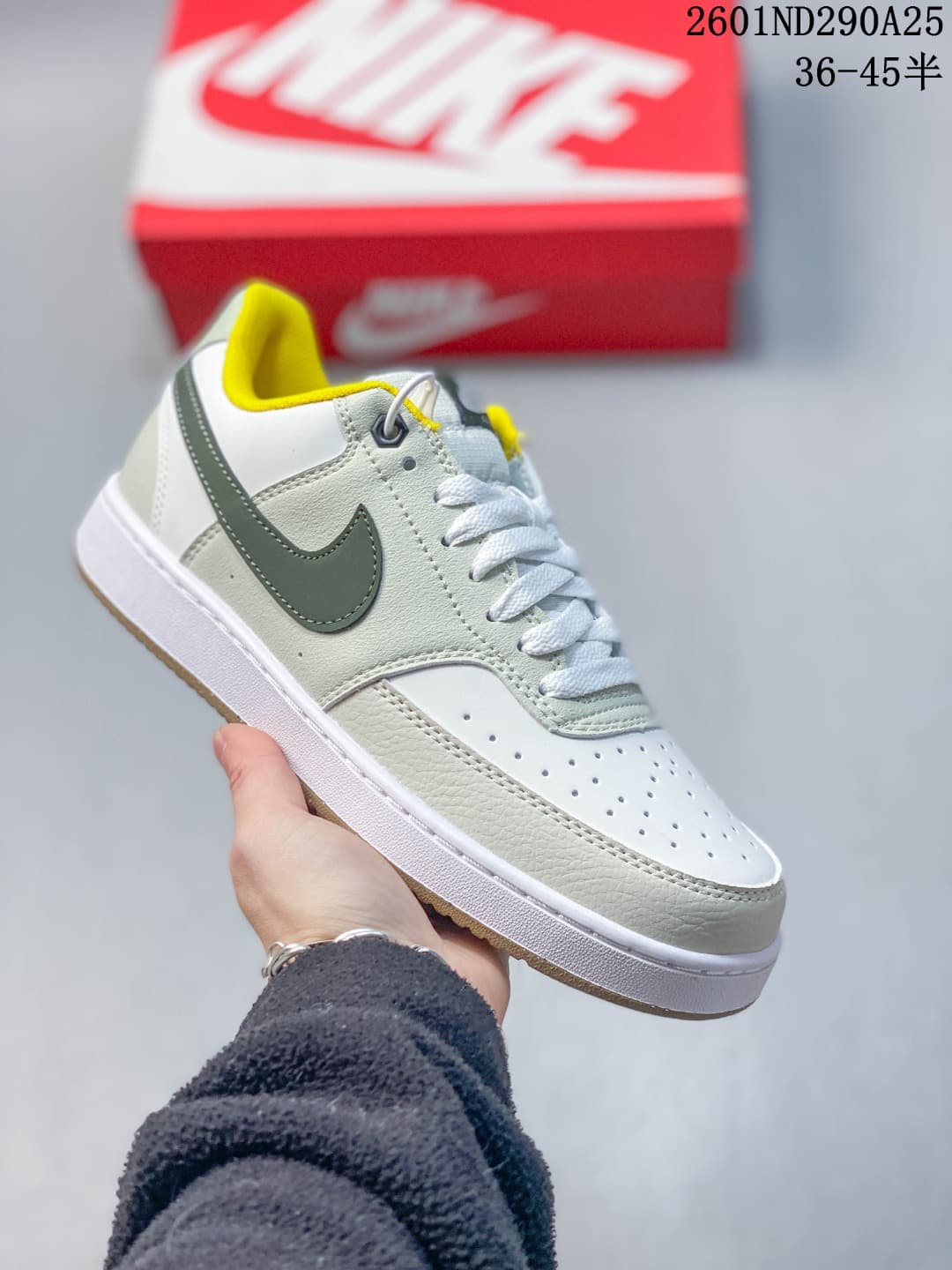 Close-up of a white and pale green low-top sneaker with a dark green Swoosh and bright yellow collar lining.