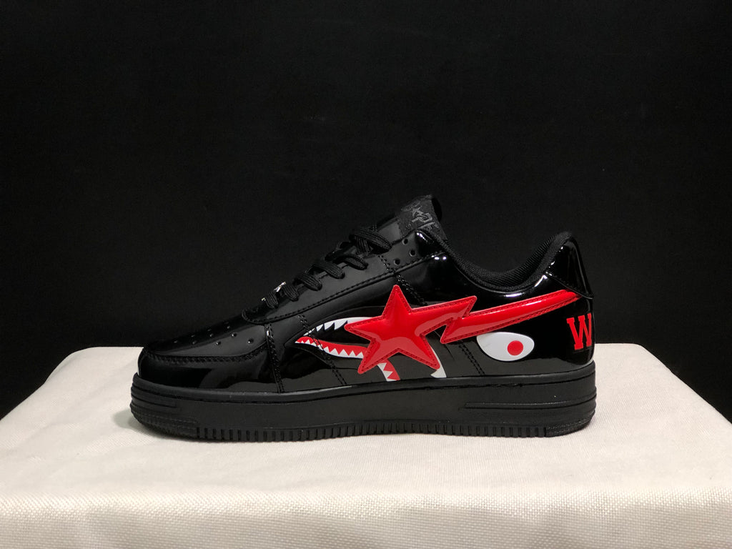 Side profile showing the low-top silhouette, glossy black panels, red star and shark graphics, and black platform outsole.