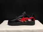 Side profile showing the low-top silhouette, glossy black panels, red star and shark graphics, and black platform outsole.