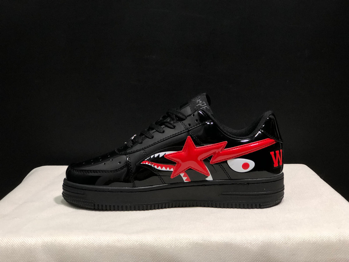 Side profile showing the low-top silhouette, glossy black panels, red star and shark graphics, and black platform outsole.