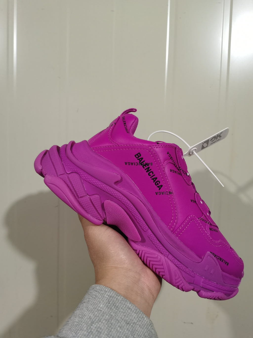 Close-up side view of a vivid purple Balenciaga sneaker showing layered panels, textured sole sections, and repeated branding.
