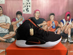 Side view of a black sneaker with an orange side swoosh, white midsole, and gum outsole