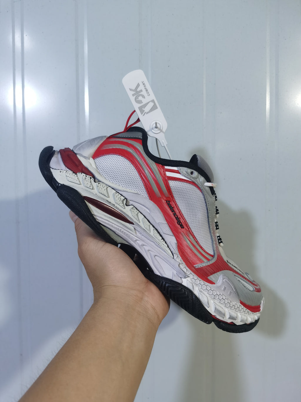 Side view of the ASICS 1169 sneaker highlighting the grey and red upper, white midsole and black outsole.