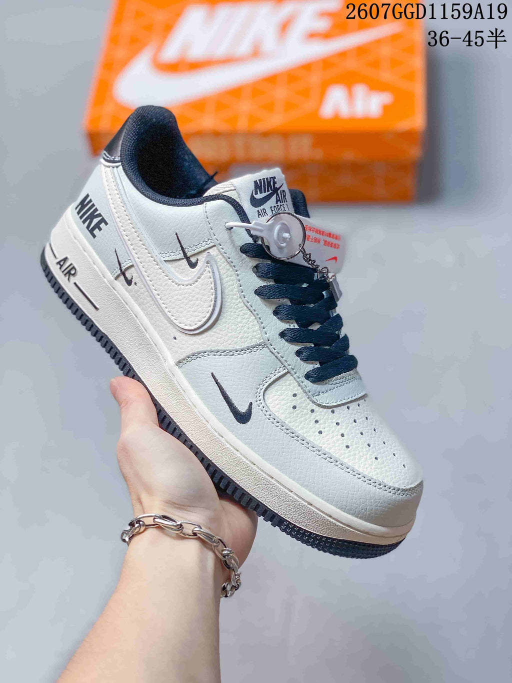 White low-top sneaker with dark blue lining, laces, Swoosh details, and a dark outsole; style code 2607GGD1159A19 and size range 36-45 are overlaid.