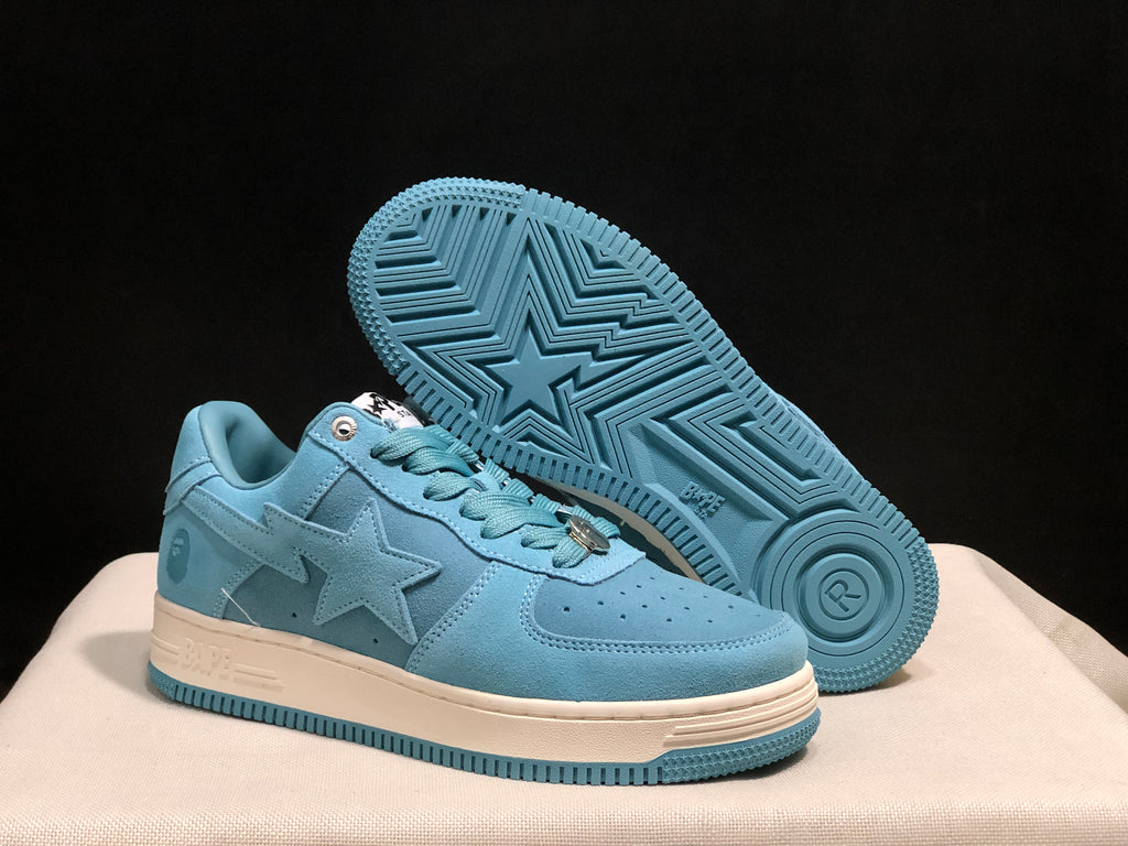 Angled view of the sneakers with one shoe lifted to display the blue outsole's geometric tread pattern and star motif.