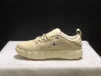 Side profile of a single cream Nike Mind 002 sneaker with silver side branding and a textured sculpted sole.