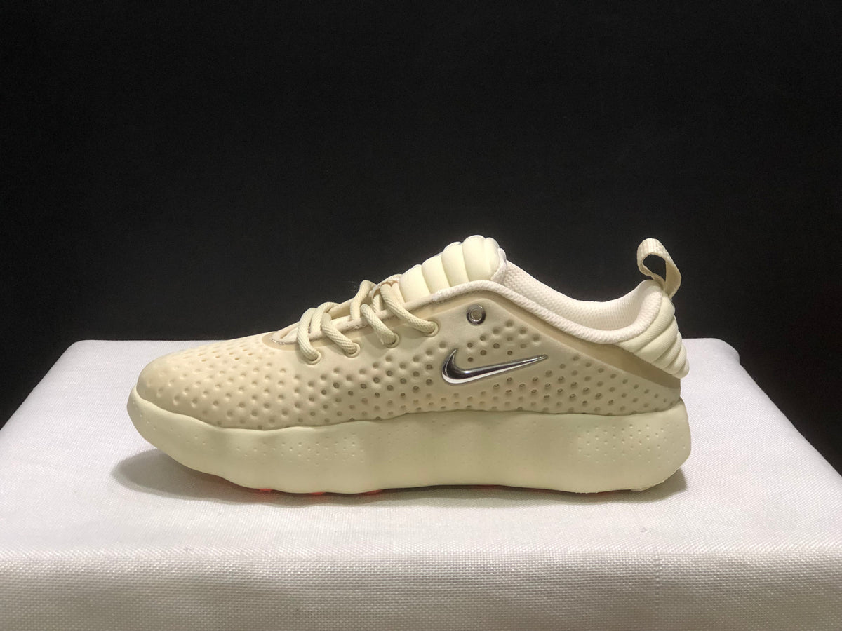 Side profile of a single cream Nike Mind 002 sneaker with silver side branding and a textured sculpted sole.