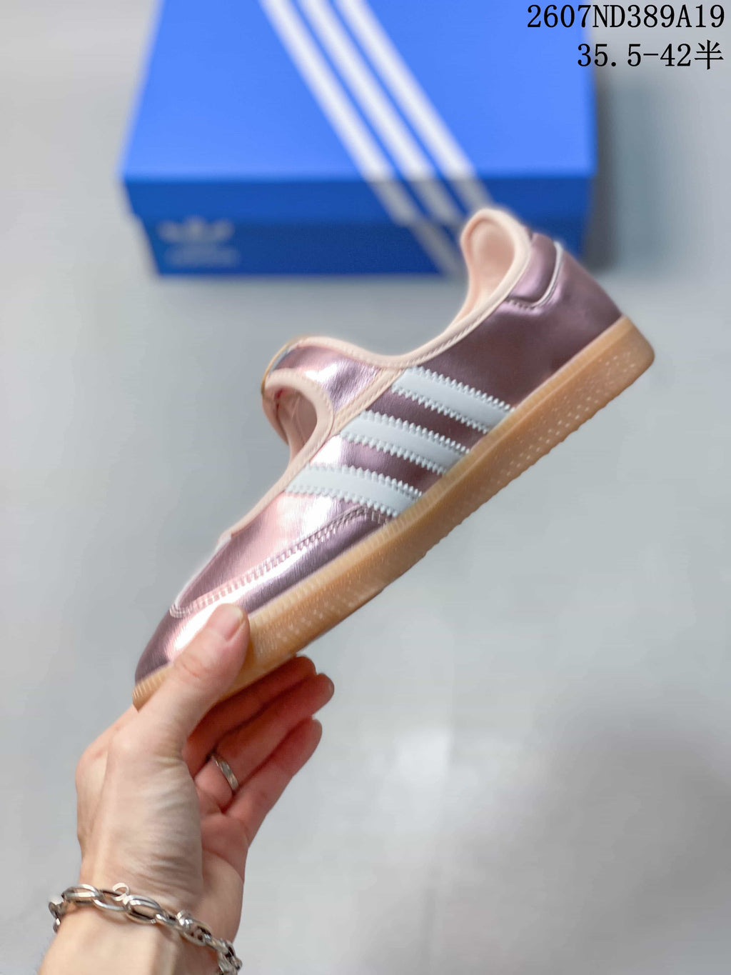 Side profile of the metallic pink sneaker showing the white three-stripe design, strap, and low gum sole.