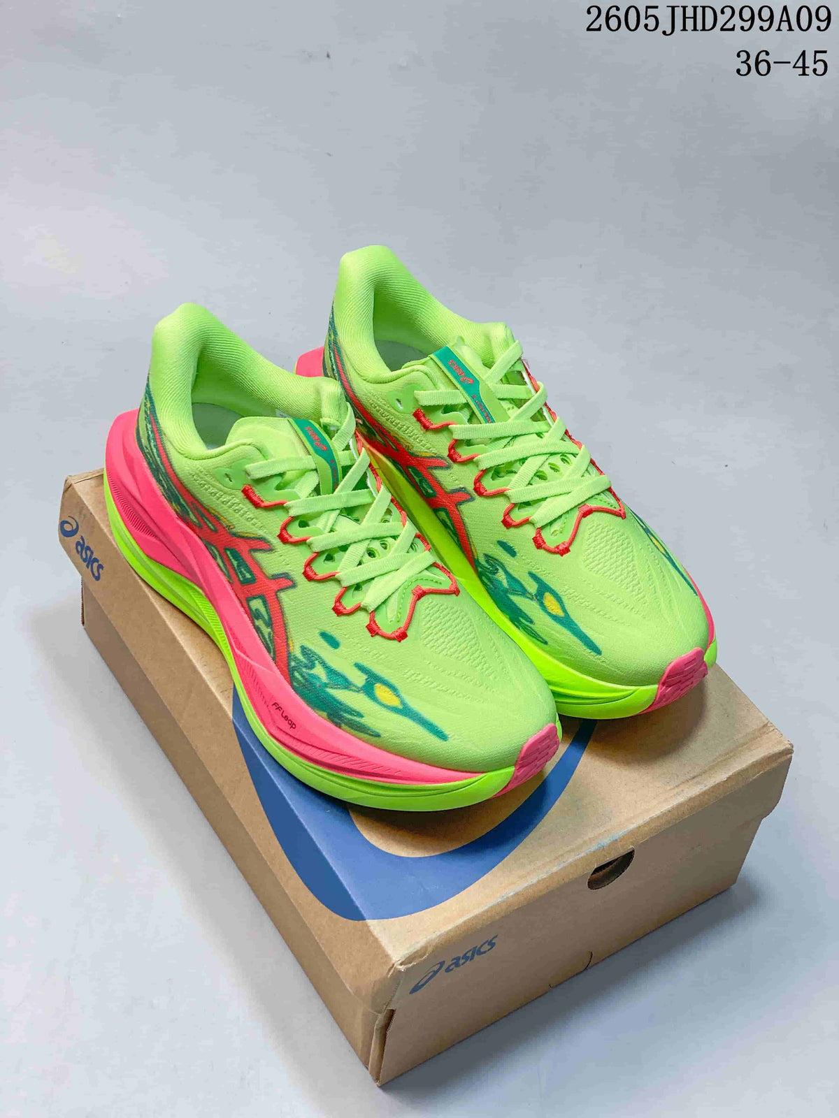 Pair of lime green ASICS Superblast 3 running shoes with pink and teal accents on a shoebox