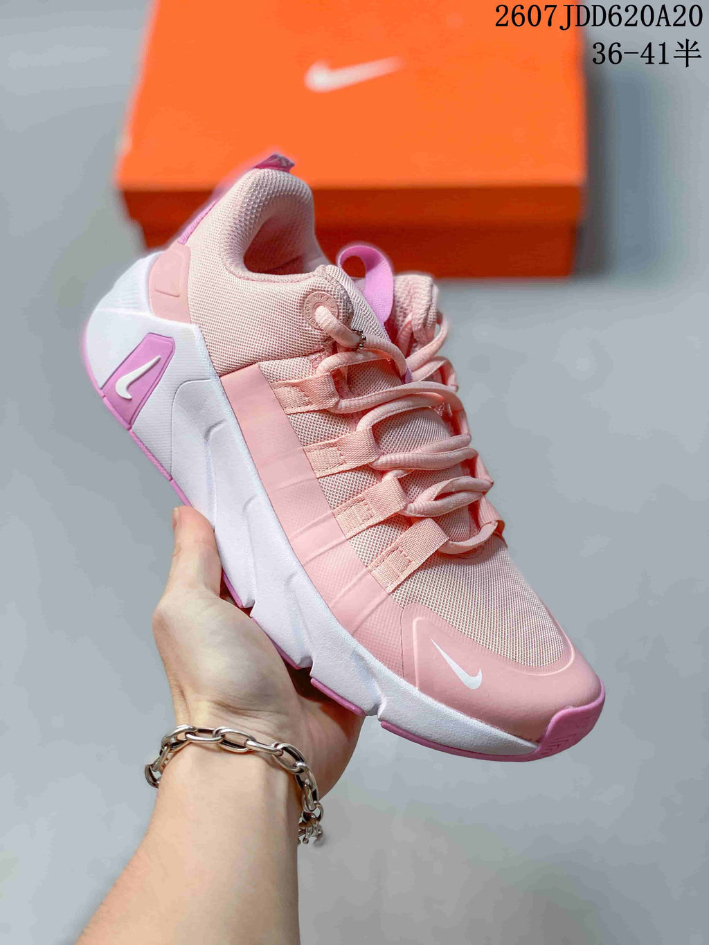 Angled side view highlighting the pink and white upper, lace supports, padded collar, heel structure, and outsole design.
