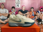 Side profile of a light beige Nike shoe with gray and teal accents and a visible side Swoosh.