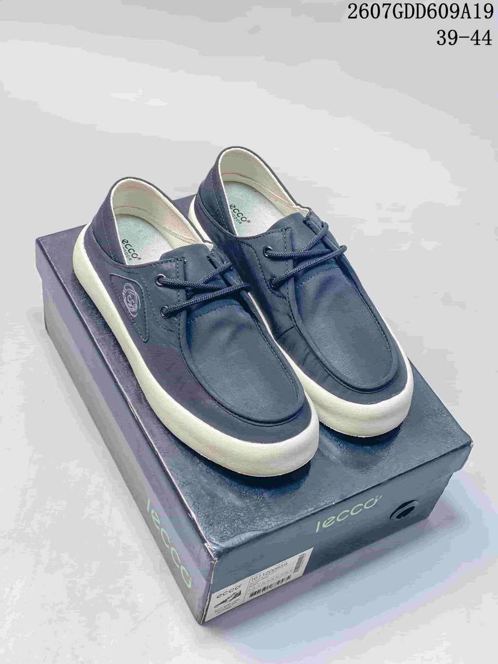 Pair of navy ECCO lace-up sneakers displayed on a branded shoebox, with product code 2607GDD609A19 and size range 39–44 visible above.