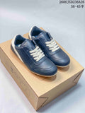 Navy low-top lace-up sneakers with white laces and heel accents, photographed on a box.