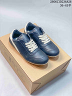 Navy low-top lace-up sneakers with white laces and heel accents, photographed on a box.