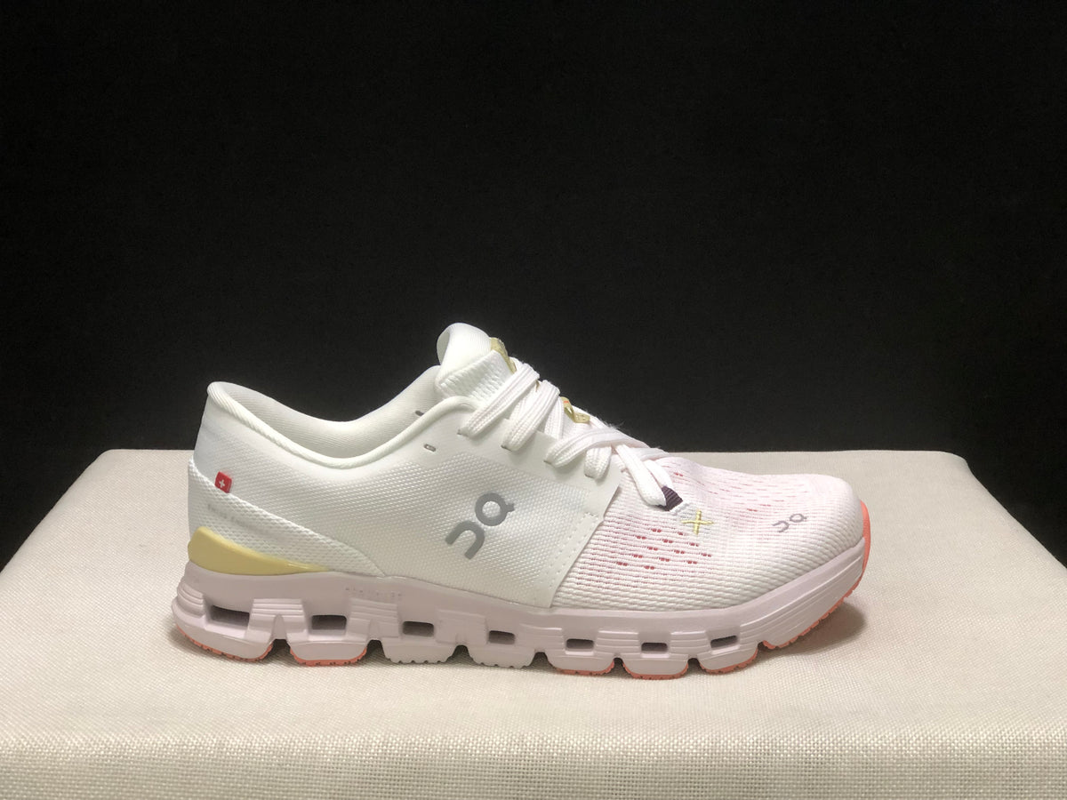 Side profile of one ivory On Cloud X4 shoe with the On logo and yellow heel insert visible.