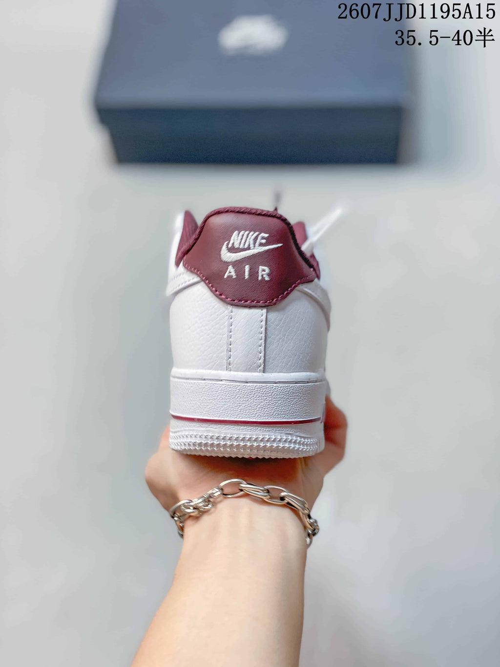 Rear view of a white low-top sneaker with burgundy heel-collar trim and Air branding.