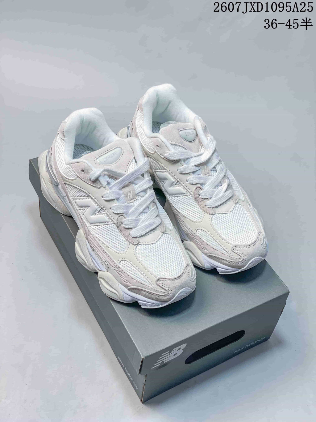 Pair of light white and cream New Balance 9060R sneakers displayed on a shoe box.